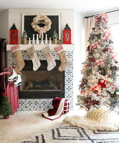 a decorated christmas tree in front of a fireplace with stockings hanging from the mantel