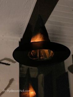 a light hanging from the ceiling in front of a white wall with two lights on it