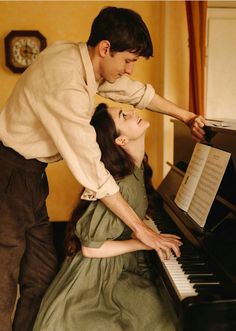 a man standing next to a woman on top of a piano