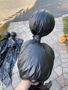 a person is holding two black trash bags