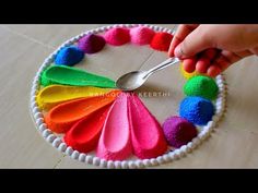 a person is holding a spoon in front of a colorful plate with pom - poms