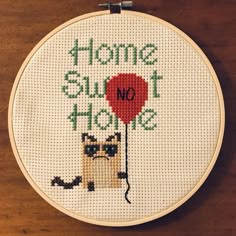 there is a cross - stitch pattern on the wall that says home sweet home with a cat holding a red balloon