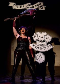 a woman in costume holding up a sign with the words little demon queen above her head