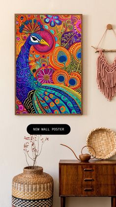 a colorful peacock painting hanging on the wall next to a wooden table and wicker basket