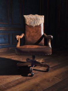 an old leather office chair sitting on top of a hard wood floor in a dark room