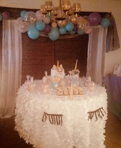 a table topped with lots of cake and cupcakes under a chandelier