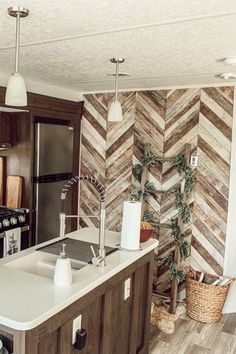 a kitchen with an island, sink and refrigerator in the middle of it is decorated with wood planks