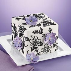 a square cake decorated with purple flowers on a plate