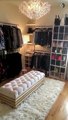 a bedroom with a bed, chandelier and closet full of clothes in it