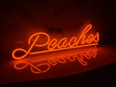 a neon sign with the word peaches written in cursive writing on it