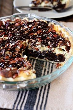 a pie with chocolate and pecans on top in a glass pie dish, ready to be eaten