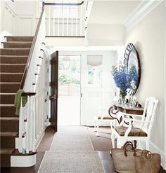 an entryway with blue and white walls, carpeted flooring and stairs leading up to the second floor