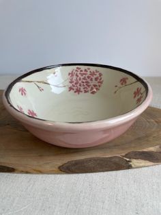 a pink and white bowl sitting on top of a wooden board