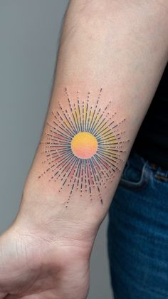 a woman's arm with a small sun tattoo on the left side of her wrist