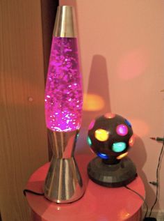 a lamp that is sitting on top of a red table next to a pink wall