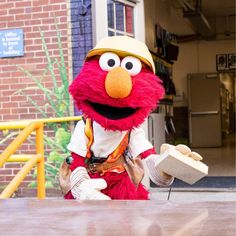 the sesame street character is sitting at a table and holding a piece of paper in his hand