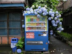 a blue vending machine sitting on the side of a road next to a building