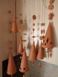 several clay bell ornaments hanging from a wall