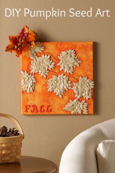 an orange and white pumpkin seed art is hanging on the wall next to a chair