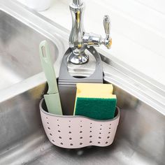 a kitchen sink with soap, sponges and cleaning utensils in the holder