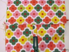 the zipper is open on top of the flowered fabric with green and red dots