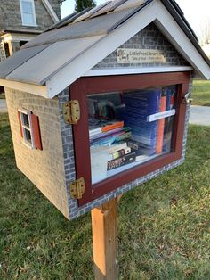 a mailbox with books in it sitting on the grass