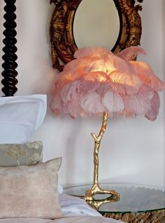 a pink lamp sitting on top of a glass table next to a mirror and pillows