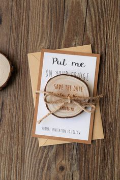 save the date card with wood slice and string tied to it on top of a wooden table