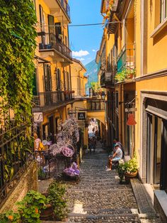 a narrow cobblestone street in an old european city with lots of plants and flowers