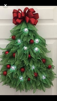 a christmas tree made out of green leaves and red berries is hanging on the front door