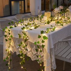 the table is set with white lace and greenery for an elegant dinner party or special occasion