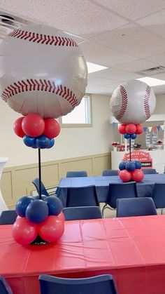 some baseball balloons are on top of tables in a room with red, white and blue decorations