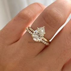 a woman's hand with a diamond ring on top of her finger and the other hand holding an engagement ring