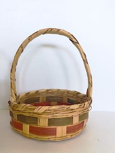 a woven basket sitting on top of a white table next to a red and green object