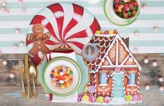 a table set for christmas with candy, candies and gingerbread house shaped plates