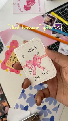 a person holding up a note with a pink bow on it and some other items in the background