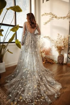 a woman standing in front of a window wearing a dress with silver stars on it