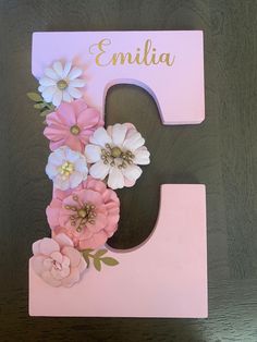 the letter e is decorated with pink and white flowers on it's front side