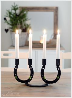 a candle holder with four candles in it on top of a wooden table next to a mirror