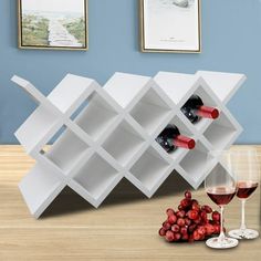 a wine rack with bottles and glasses on a table next to a glass of wine