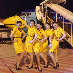 a group of women in yellow uniforms standing next to an airplane