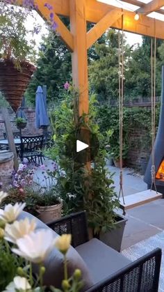 an outdoor fireplace in the middle of a patio with lots of flowers and plants around it