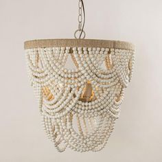 a white chandelier hanging from the ceiling with beads and jujut trim