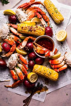 lobsters, corn on the cob, and potatoes are laid out on newspaper