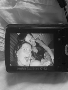 a black and white photo of two women on a camera with the screen showing an easyshare c34