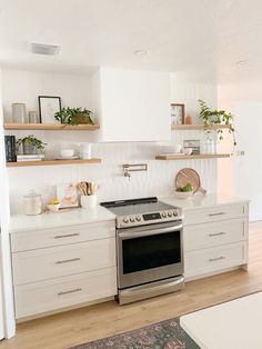 a kitchen with white cabinets and stainless steel stove top oven in the middle of it