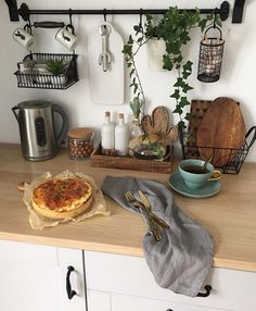 a kitchen counter topped with a pizza on top of a wooden counter next to pots and pans