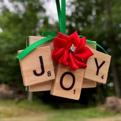 a wooden block ornament with the word joy and a red flower on it