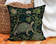 a decorative pillow with an image of a turtle and flowers on it, next to a wicker basket