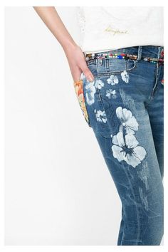 a woman wearing jeans with flowers painted on them